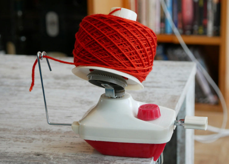 Red yarn ball on a yarn winder with a blurred background